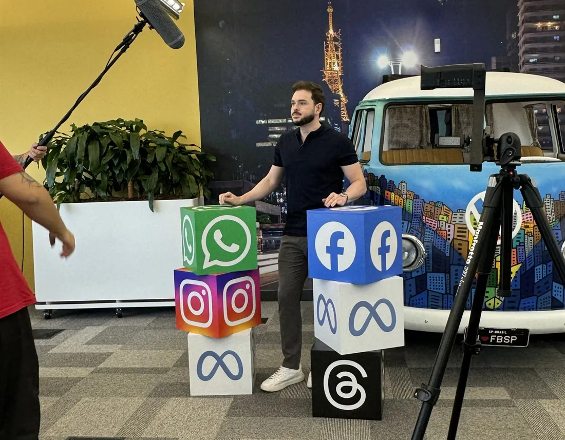 Lucas Renault gravando conteúdo em evento da Meta, entre cubos com os logos de WhatsApp, Instagram e Facebook